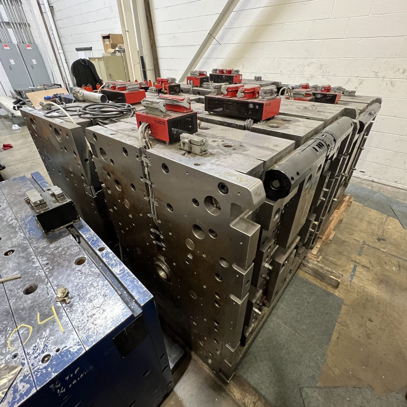 A large injection mold resting on a pallet on the plant floor.