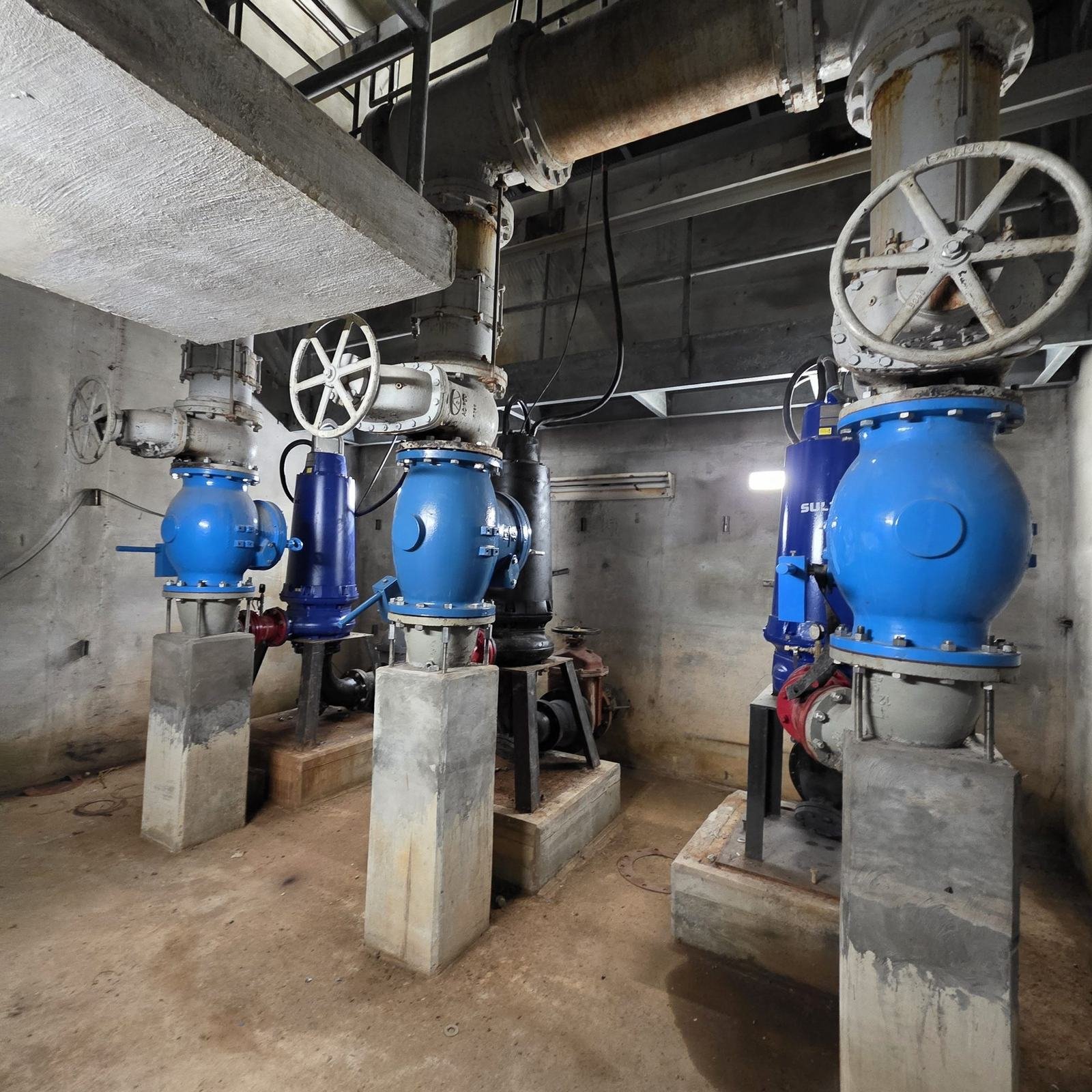 Pumps and large blue valves inside a wastewater pump station.